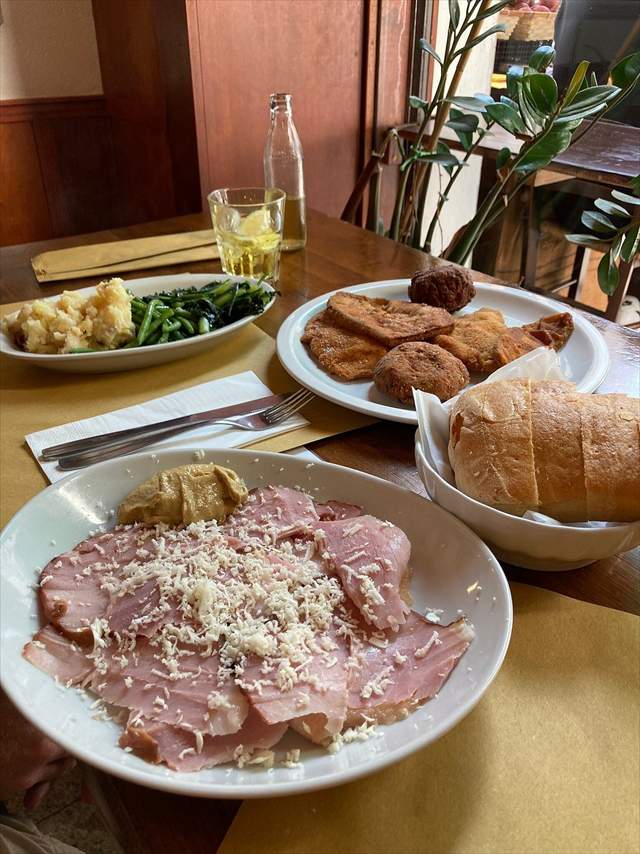 Prosciutto cotto tagliato a mano con cren e senape, polpette, pane e un calice di vino bianco